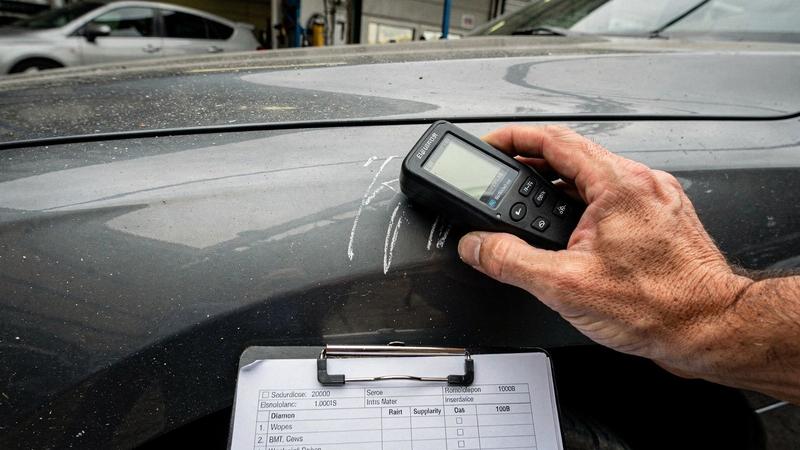 Inspection photo of a front wing with a paint depth gauge reading 214 micrometres